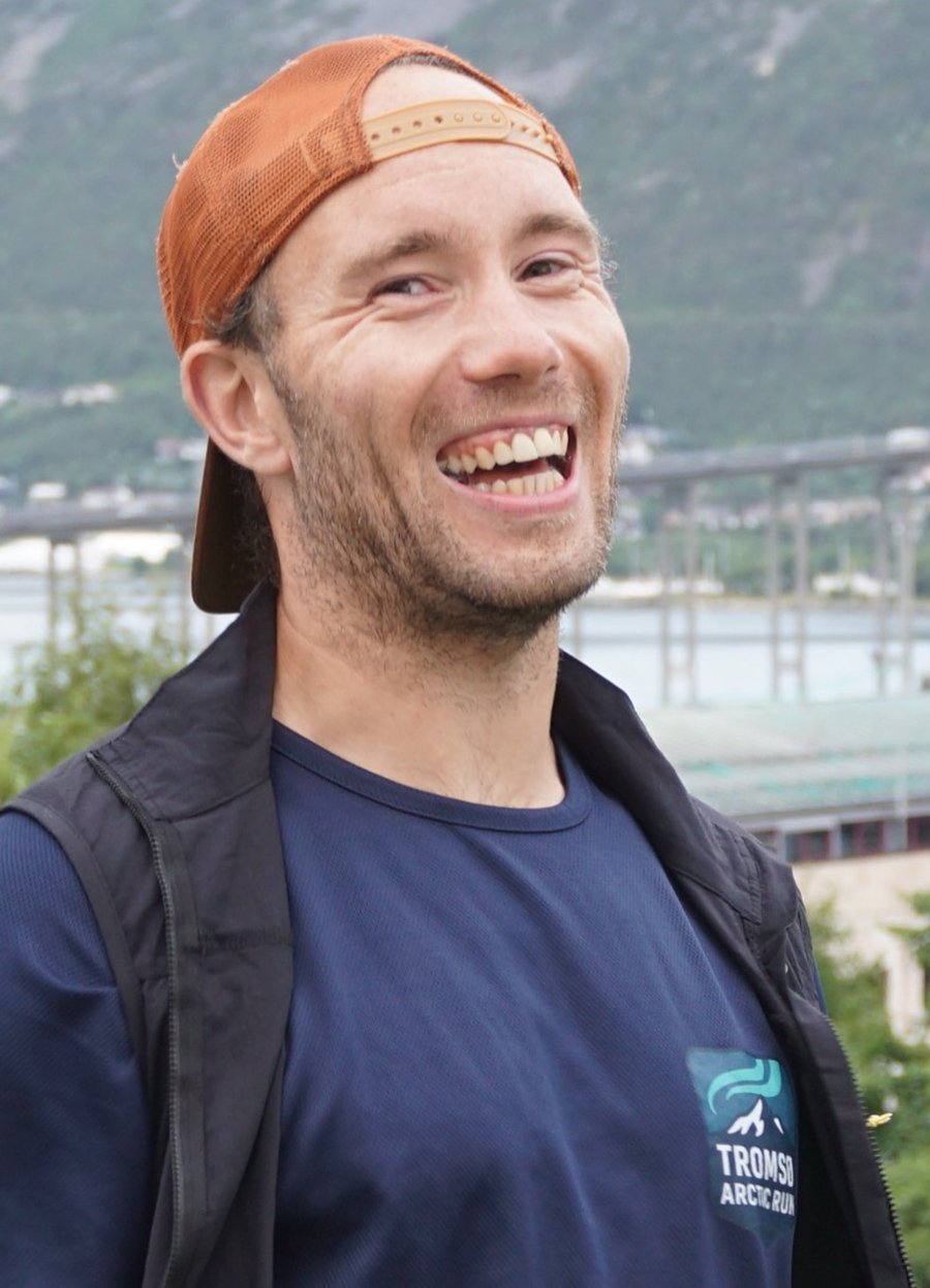 Kristoffer, founder of Tromsø Arctic Run, laughing above the city with the fjord and mountains behind him