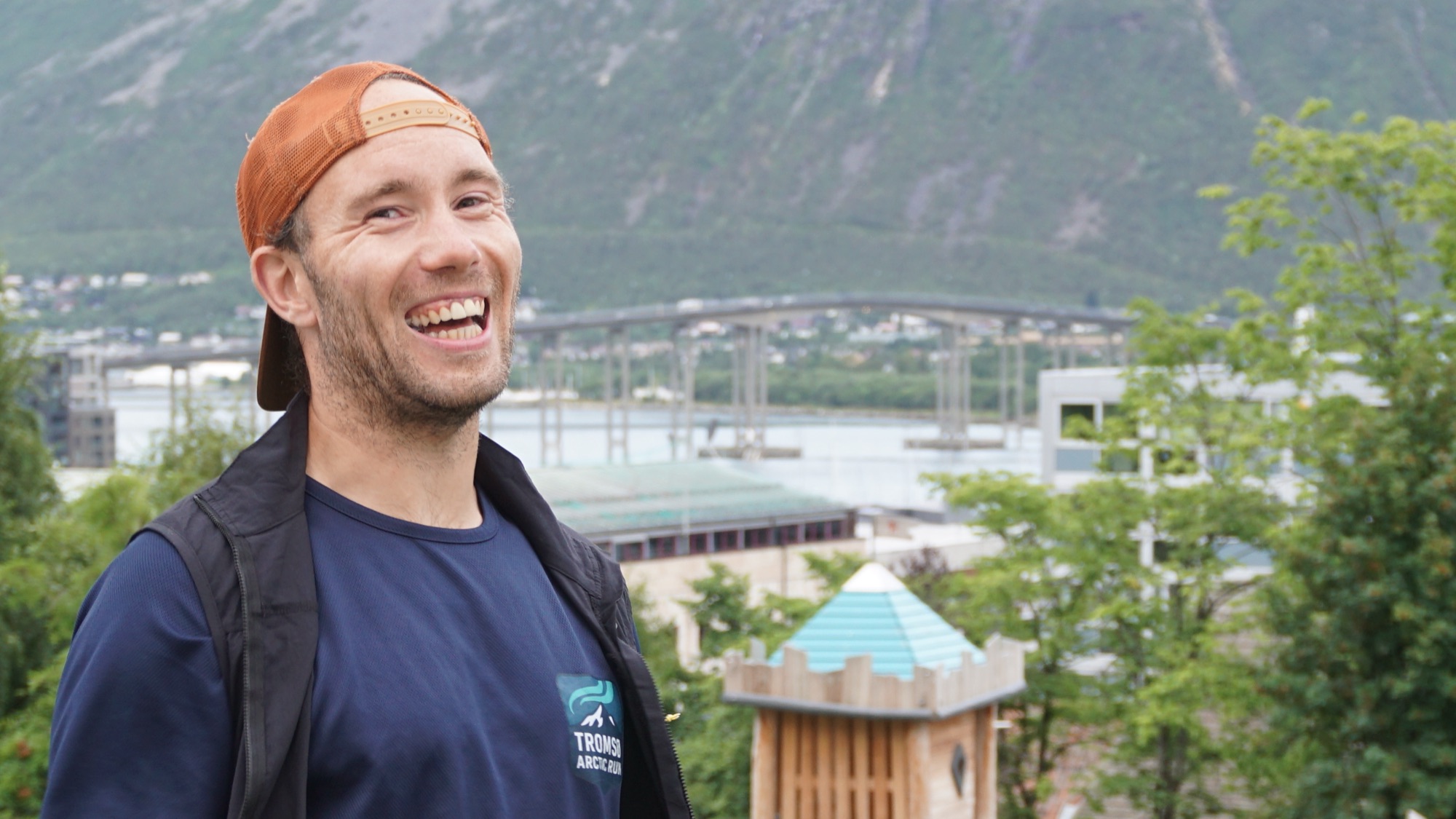 Kristoffer, founder of Tromsø Arctic Run, laughing above the city with the fjord and mountains behind him