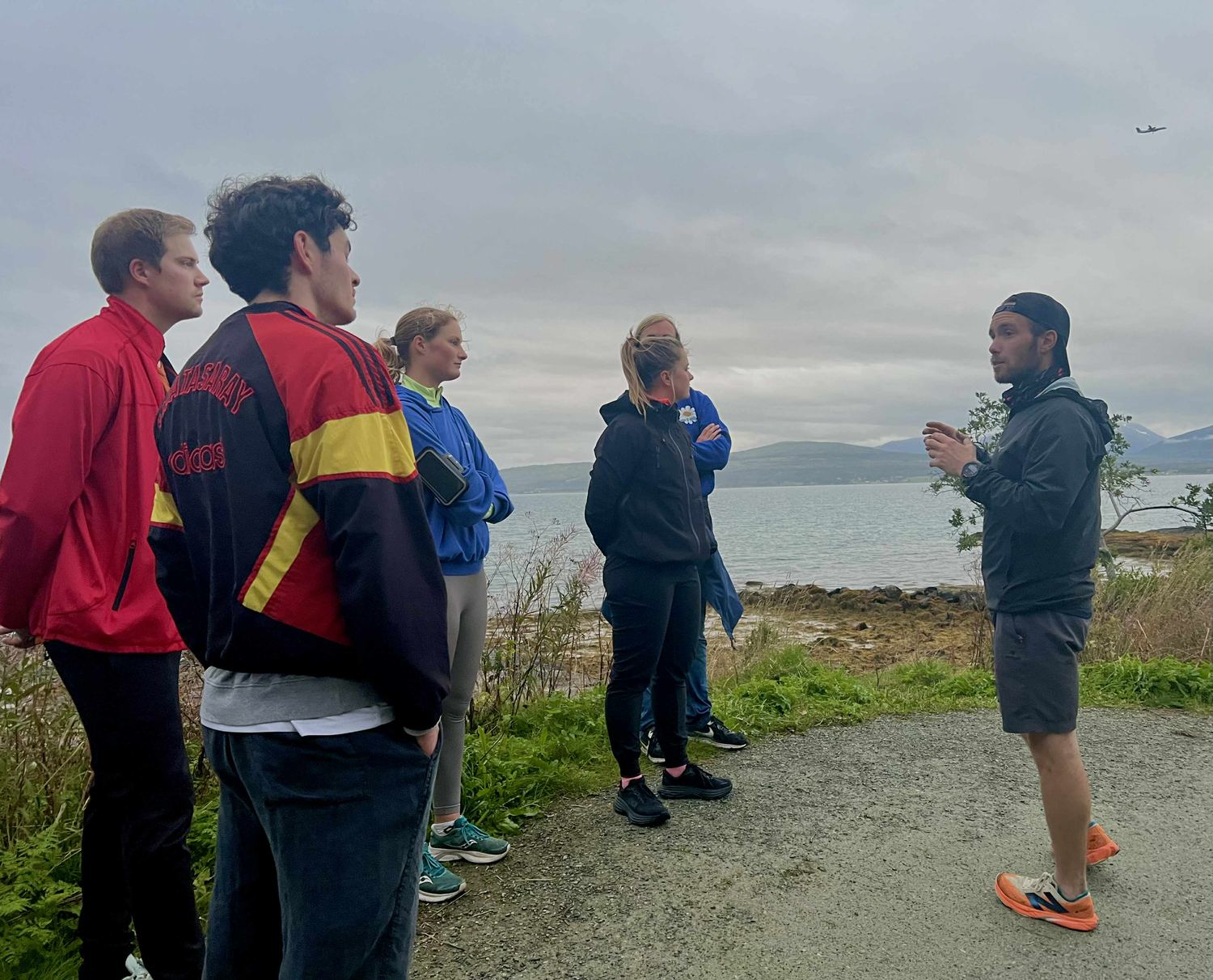 A guide talking to a small group of guests who are listening beside the fjord in Tromsø