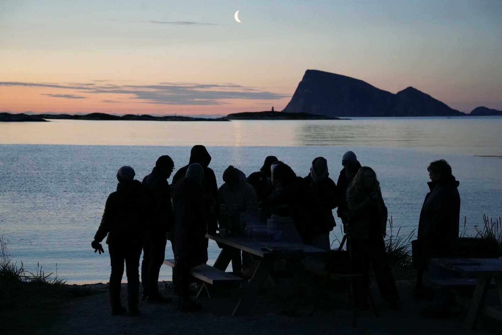 A Snow Travels tour group gathered on the shoreline at dusk
