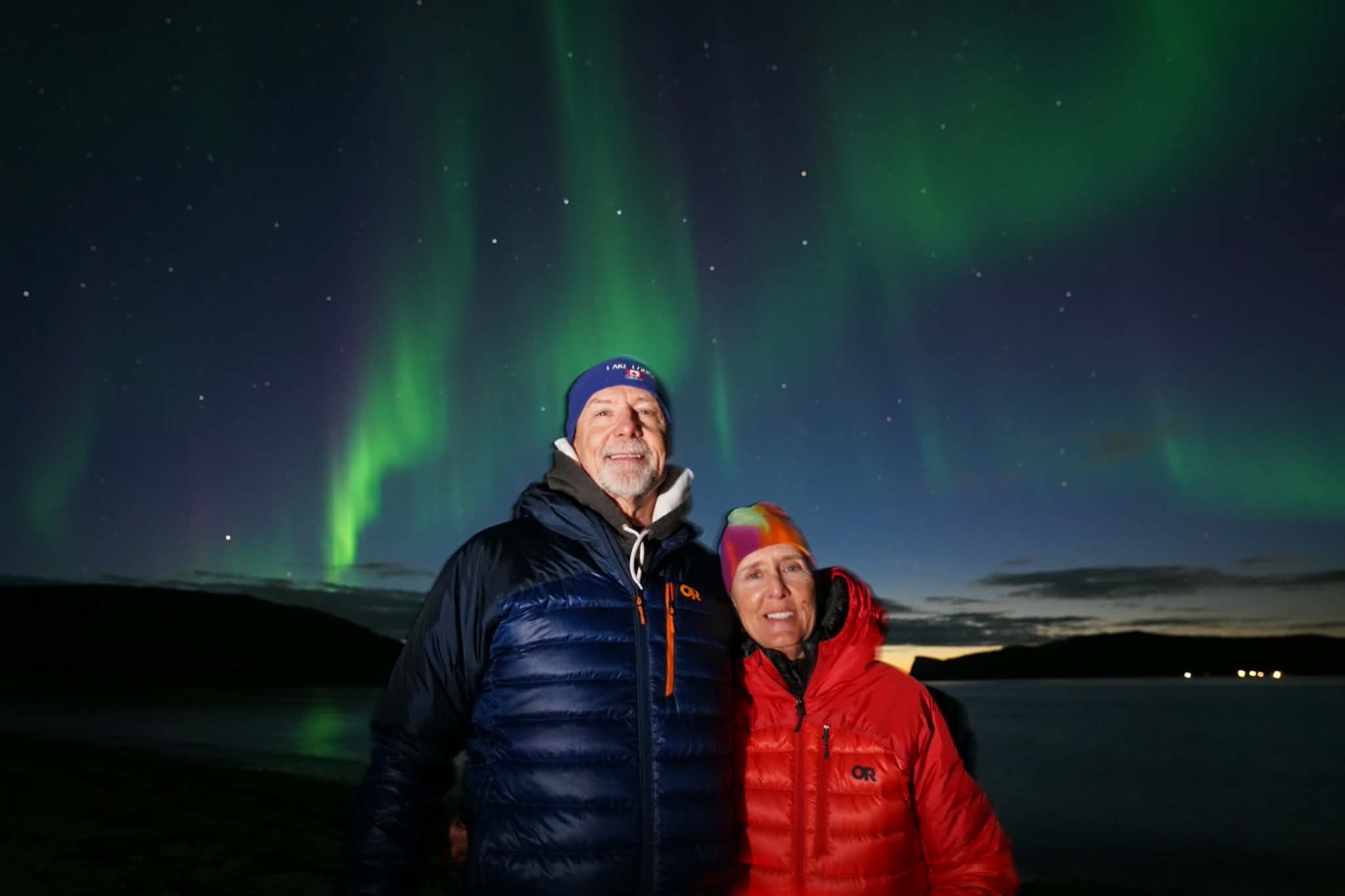 Guests smiling under a bright green aurora on a Snow Travels tour