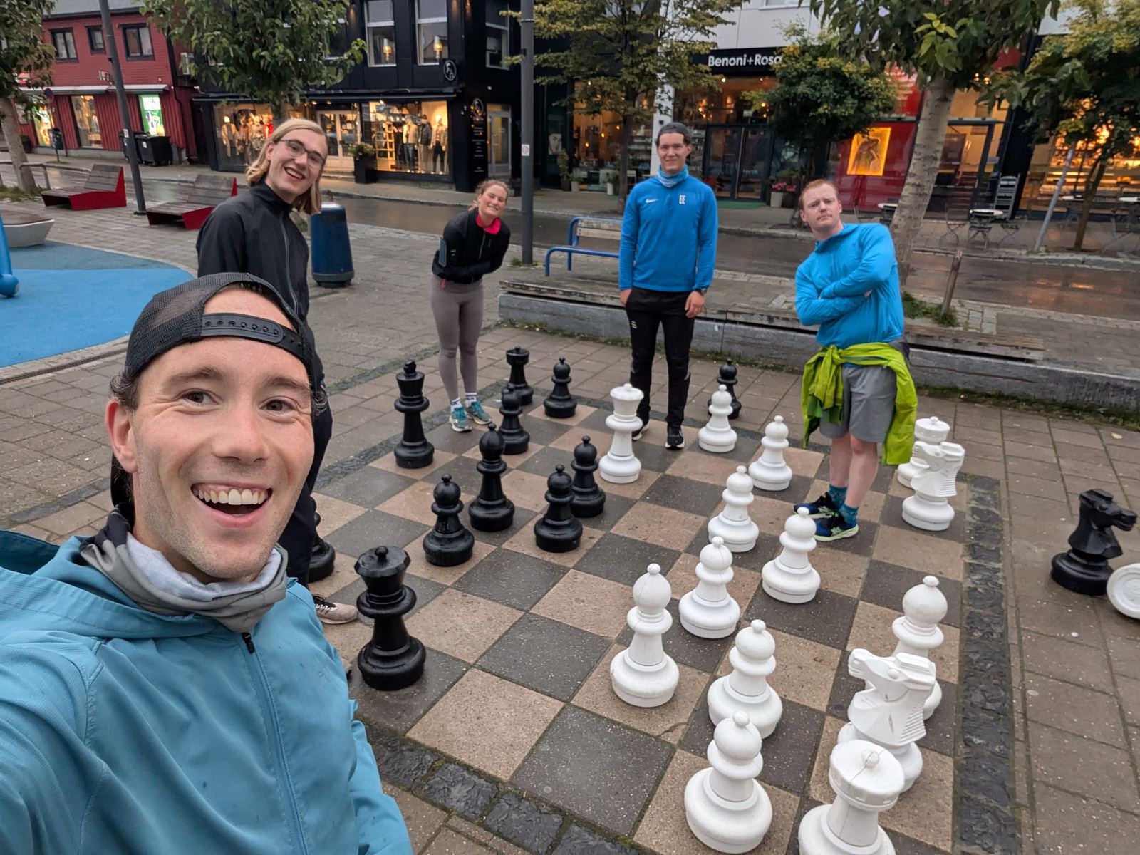 A guide taking a selfie with guests beside a giant chess board and the Roald Amundsen statue in Tromsø